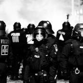 A group of men in german police gear wearing helmets. One man is looking straight at the camera.