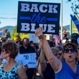 Protesters gathered. A woman holds up a sign that read Back the Blue.