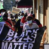 Protesters holding a black lives matter flag and walking