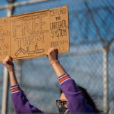 A sign on cardboard says "Fuck 12, Defund CPD, Abolish ICE, Free them All, Defund the Carceral System, Free them all"