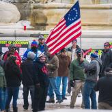 Crowd wearing winter clothes holding colonial American flag