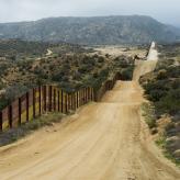 Long dirt road along border wall
