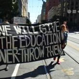 Protesters holding a banner that reads: No one will give you the education to overthrow them