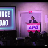 Man standing on stage next to Powerpoint that reads "Vince Dao"