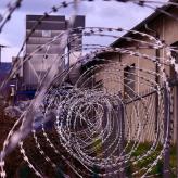 Barbed wire in a spiral form outside a brown building.